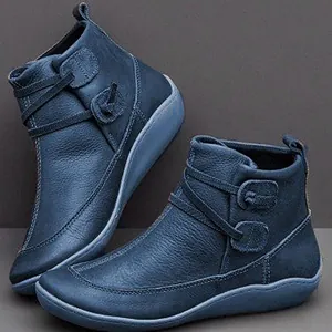 Détail de bottines en cuir bleu avec brides enveloppantes et semelles plates confortables.