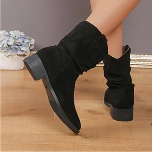 Close-up detail view of women's black suede slouchy western cowboy boots worn on wooden floor