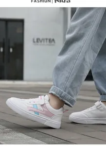Zapatillas de cuero blanco para niños con rayas rosa y azul, vista de detalle en calle.