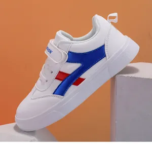 Vista lateral de zapatillas blancas para niños con rayas azules y rojas y cierre velcro.
