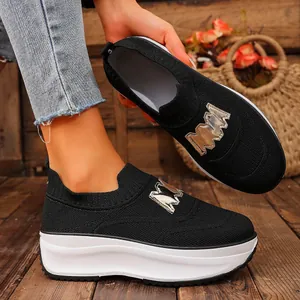 Close-up of black knit platform sneakers featuring a stylish gold M metal buckle