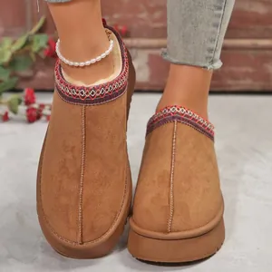 Gros plan de pantoufles mules en daim marron chaud avec plateforme épaisse et garniture.