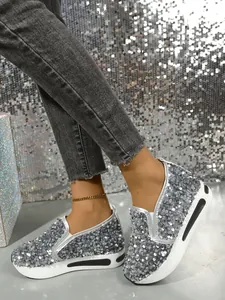 Detailansicht der silbernen Pailletten-Loafer für Damen auf Füßen vor Glitzerhintergrund