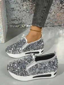 Nahaufnahme von silbernen Pailletten-Slippern für Damen mit dicker weißer Plateausohle.
