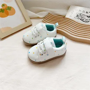 Close-up of white baby walking shoes with colorful star pattern and Velcro straps