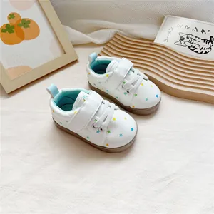 Close-up detail of white baby walker shoes featuring colorful star prints and velcro strap.
