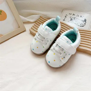 Toddler white leather walking shoes featuring colorful star patterns on a wave wooden tray