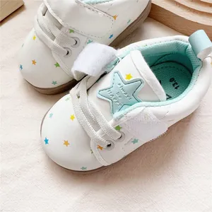 Close-up detail of white baby walking shoes featuring colorful star patterns and soft soles