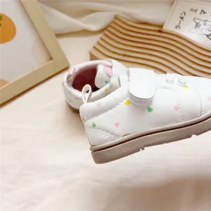 Detailed view of white toddler walking shoes with soft soles and cute heart patterns.