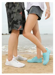 Close-up detail of quick-dry surfing water shoes for couples on sandy beach landscape