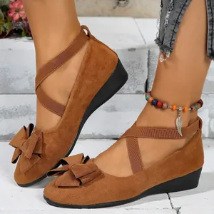 Stylish brown suede wedge shoes featuring a decorative bow and elastic cross straps for women