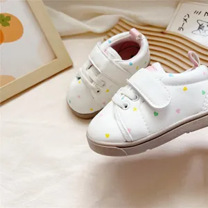 Detail of baby soft sole walking shoes featuring a colorful heart pattern on white leather