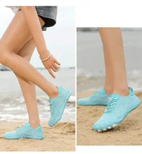 Detail view of breathable cyan quick-dry aqua shoes worn on a sunny sandy beach