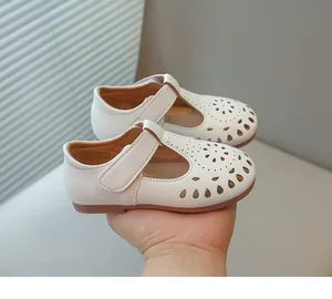 Detailed macro view of white girls' hollowed-out leather princess shoes held by hand