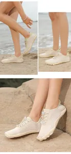 Detail view of breathable beige quick-dry aqua shoes worn on sandy beach rocks.