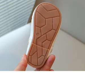 Macro view of brown non-slip rubber sole on white children princess shoes with size 23 mark.