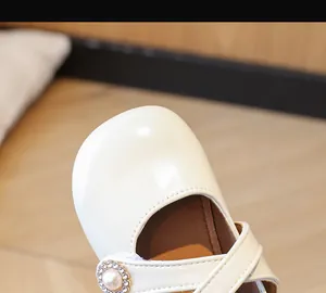 Nahaufnahme eines weißen Prinzessinnenschuhs für Mädchen mit eleganter Perle und Kristallen.