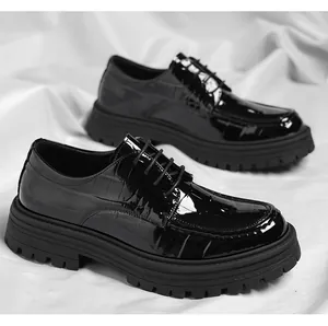 Gros plan de chaussures à plateforme pour hommes en cuir verni noir à texture croco.