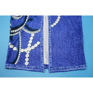 Primer plano del detalle de un vestido con estampado denim azul, perlas y costuras finas.