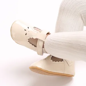 Detail of beige patent leather baby princess shoes with scalloped edges and floral cut-outs