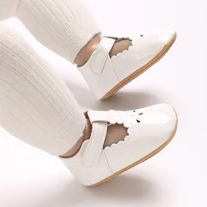 Close-up of white patent leather baby princess shoes with scallop edges and velcro strap