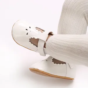 Detail of white patent leather baby Mary Jane shoes with scallop edges and rubber sole