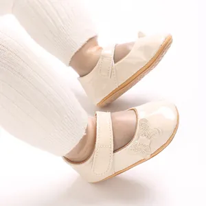 Close-up of cream glossy baby Mary Jane shoes with a beautiful glittery bow detail