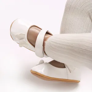 Close-up of white patent leather baby princess shoes with butterfly bow detail
