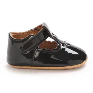 Detail of black patent leather baby princess shoe with scalloped edges and T-strap