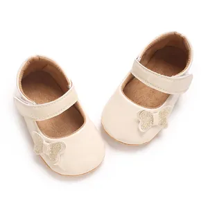 Macro detail of cream baby princess shoes with sparkly butterfly bows and adjustable velcro strap.