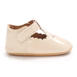 Detailed side view of cream patent leather baby princess shoe with scallop trim and T-strap.
