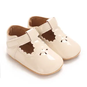 Detail of glossy beige baby Mary Jane shoes featuring scallop edges and a Velcro T-strap