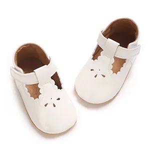 Close-up of white patent leather baby princess shoes with scalloped edges and floral cutouts