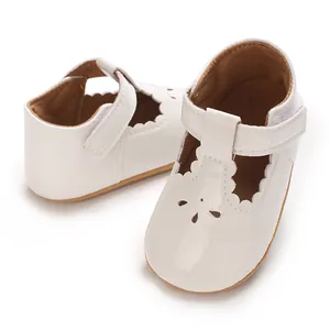 Detailed view of white patent leather baby princess shoes with scalloped edges and Velcro strap