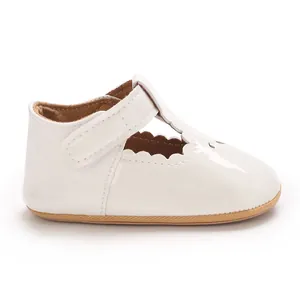 Close-up of white patent leather baby princess shoe with scallop trim and T-strap.