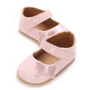 Close-up detail of soft pink patent baby princess shoes featuring a glitter butterfly bow