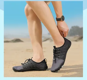 Detailed view of gray barefoot wading shoes being worn on a sunny sandy beach context.