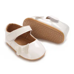 Close-up view of white patent leather baby princess shoes with butterfly bow detail