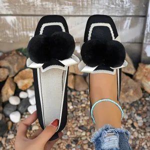 Dettaglio dei mocassini invernali neri slip-on con pompon soffici e calda fodera interna
