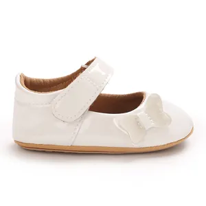 Side view of a glossy white baby girl Mary Jane shoe with a cute butterfly detail