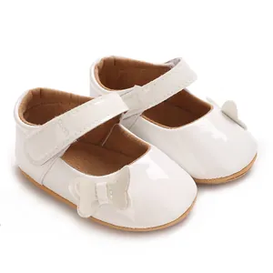 Close-up detail of white patent leather baby girl princess shoes with butterfly bow decor