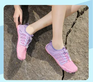 Outdoor detail view of pink and purple five-finger barefoot water shoes on rocky ground
