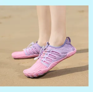 Primo piano di scarpe da wading a piedi nudi a cinque dita rosa e viola su una spiaggia.