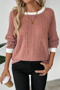Close-up detail of women's dusty pink ribbed knit sweater with white contrast cuffs
