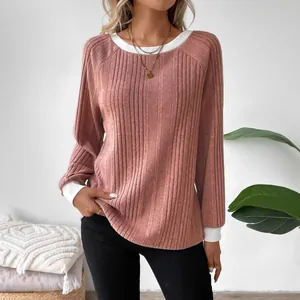 Close-up view of pink ribbed knit sweater featuring white crew neck and contrast cuffs.