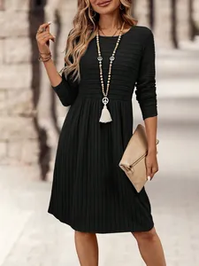 Close-up detail of a black long-sleeved ribbed dress paired with a tassel necklace.