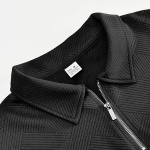 Detalle de tejido jacquard negro con cuello de polo y cremallera metálica