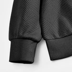 Detalle de los puños acanalados y el tejido jacquard texturizzato de una sudadera polo negra.