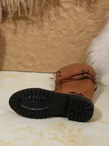 Détail de bottes cavalières marron à lacets avec semelle crantée et boucles.