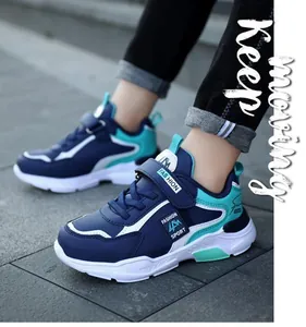 Side view of navy blue and teal boy's sports shoes with velcro straps on pavement